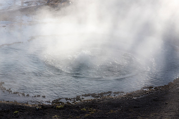 Sun rays shine down on Firehole Spring